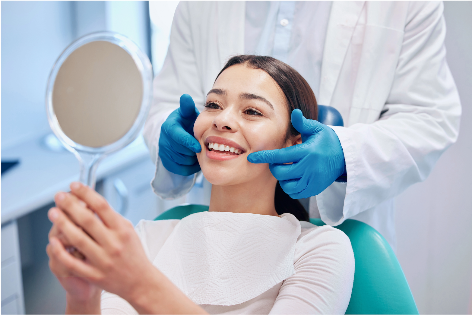 Happy woman smiling and checking her teeth in a mirror at a dental clinic in Alanya