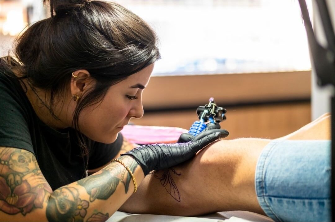 Professional female tattoo artist working on a leg tattoo in Alanya studio